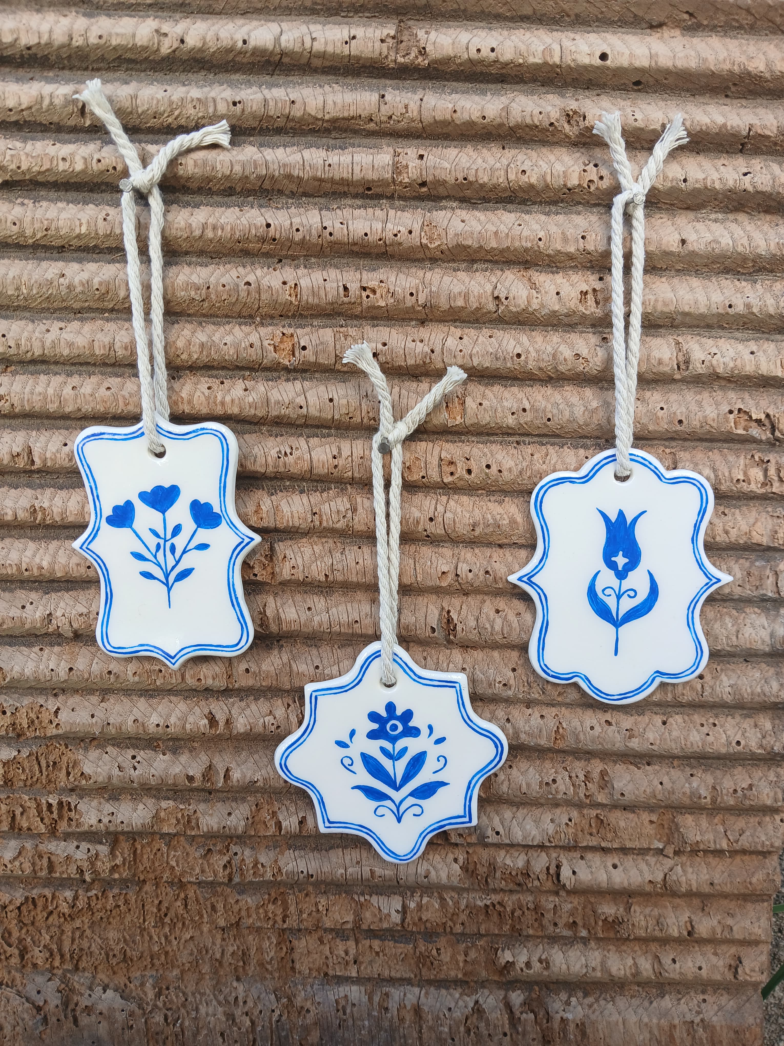 Trio floral tulipe, fleur folk et branche fleurie en argile blanche peinte en bleu, suspendu à du bois
